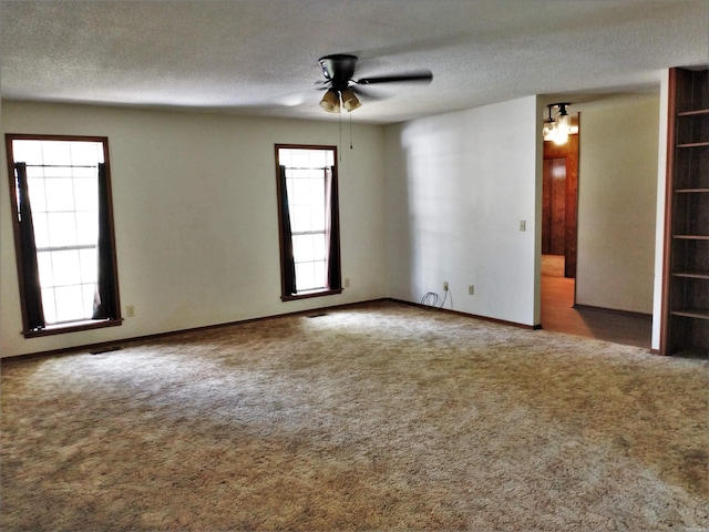 spare room with a textured ceiling, ceiling fan, and dark colored carpet