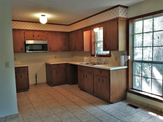 kitchen featuring ornamental molding, a wealth of natural light, light tile floors, and sink