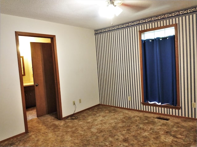 carpeted empty room featuring ceiling fan and a textured ceiling