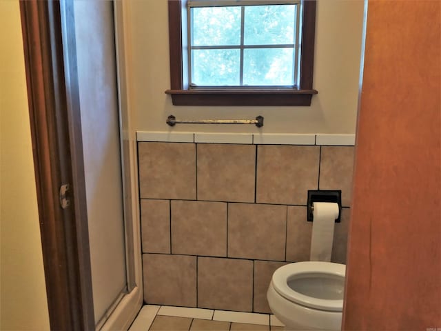 bathroom with tile walls, toilet, and tile floors