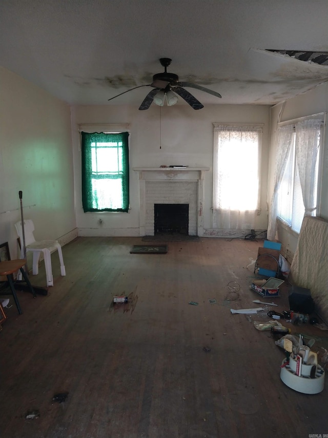 unfurnished living room with hardwood / wood-style floors, ceiling fan, a wealth of natural light, and a fireplace