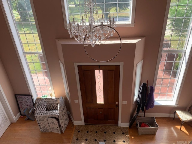 entryway with an inviting chandelier, a wealth of natural light, and light hardwood / wood-style floors