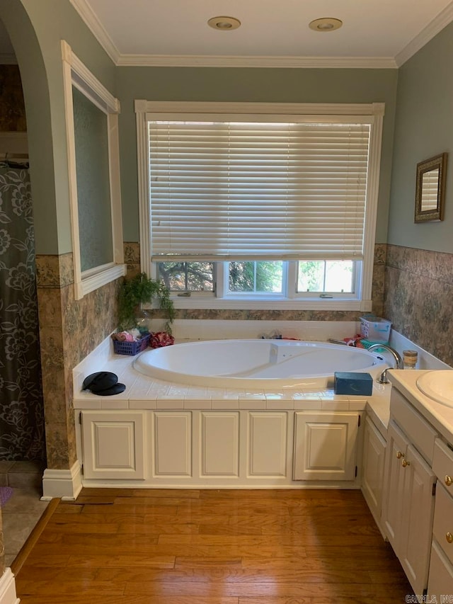 bathroom featuring vanity, hardwood / wood-style floors, crown molding, and a tub