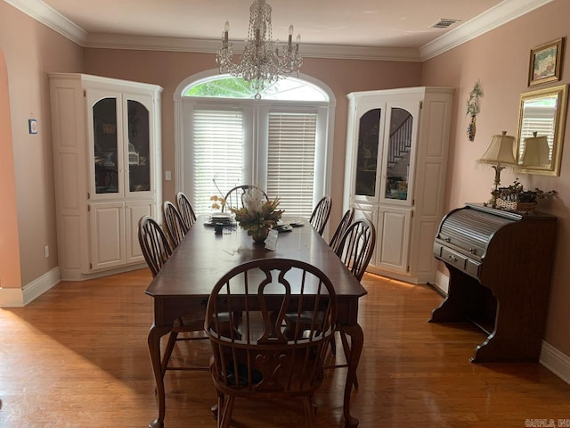 dining space featuring a chandelier, light hardwood / wood-style floors, and crown molding