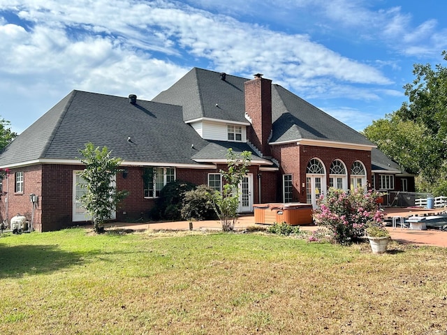 rear view of house featuring a hot tub and a yard