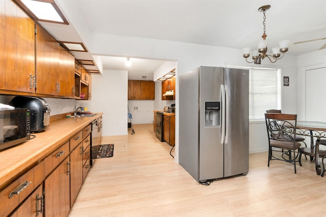 kitchen with decorative light fixtures, light hardwood / wood-style floors, stainless steel appliances, a notable chandelier, and sink