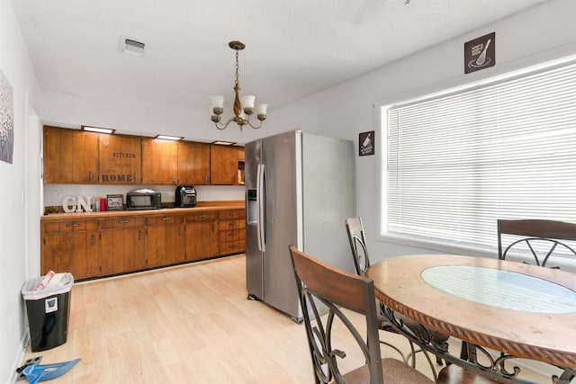 kitchen featuring stainless steel fridge, light wood-type flooring, a chandelier, and pendant lighting