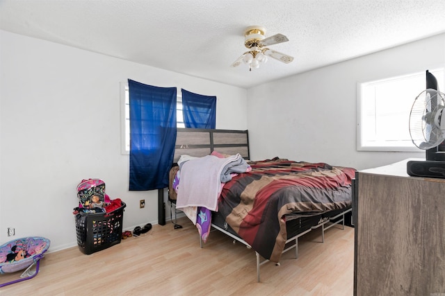 bedroom with a textured ceiling, ceiling fan, and light wood-type flooring