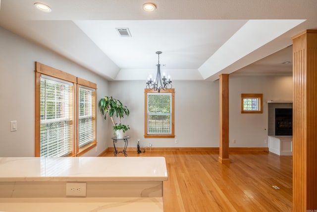 interior space with a chandelier, a tray ceiling, and light hardwood / wood-style flooring