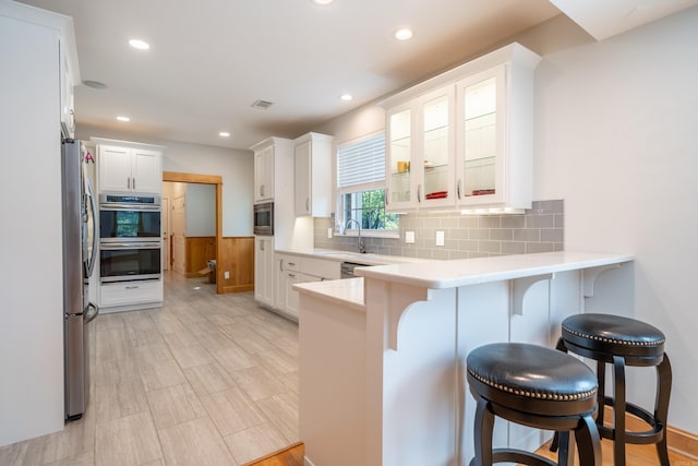 kitchen with tasteful backsplash, a kitchen bar, appliances with stainless steel finishes, and kitchen peninsula