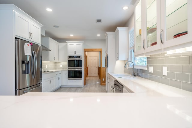 kitchen with white cabinets, appliances with stainless steel finishes, tasteful backsplash, and sink