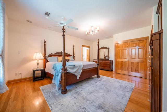 bedroom with a closet, ceiling fan with notable chandelier, and light wood-type flooring