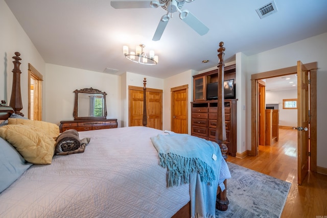 bedroom featuring multiple windows, ceiling fan with notable chandelier, and light hardwood / wood-style flooring