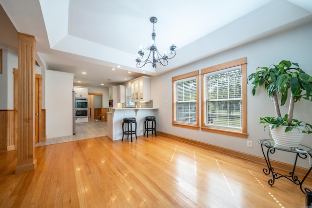 living room with an inviting chandelier, a tray ceiling, and light tile floors