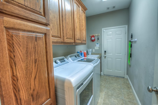 laundry area featuring cabinets, light tile floors, washer and dryer, and sink