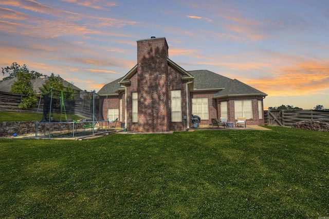 back house at dusk featuring a yard and a patio