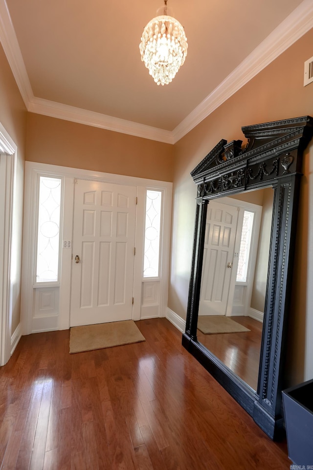 entrance foyer featuring dark hardwood / wood-style flooring, a notable chandelier, and ornamental molding