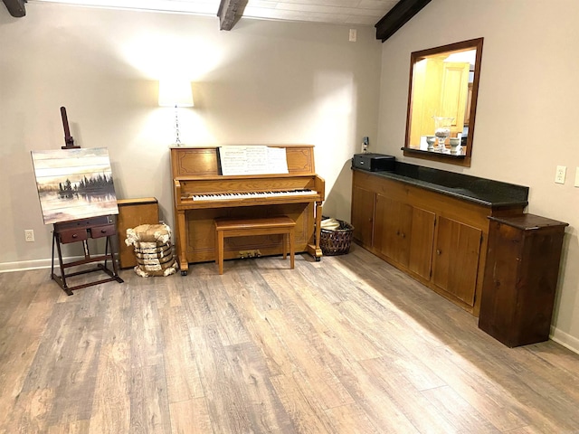 bedroom with vaulted ceiling with beams and light wood-type flooring