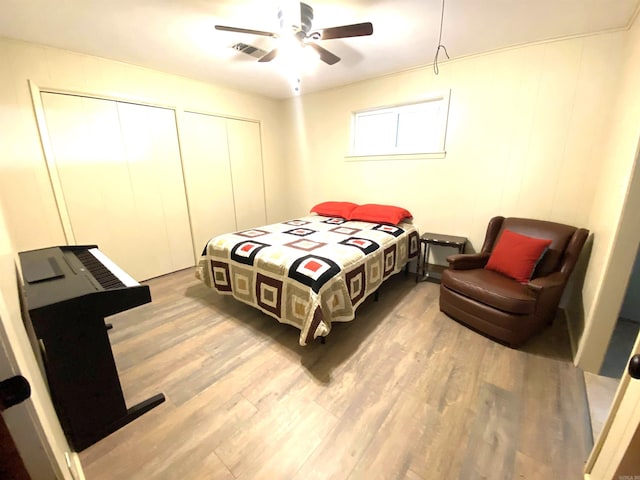 bedroom featuring ceiling fan, two closets, and light hardwood / wood-style floors