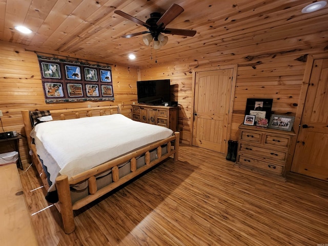 bedroom featuring wooden ceiling, ceiling fan, wood walls, and light hardwood / wood-style flooring