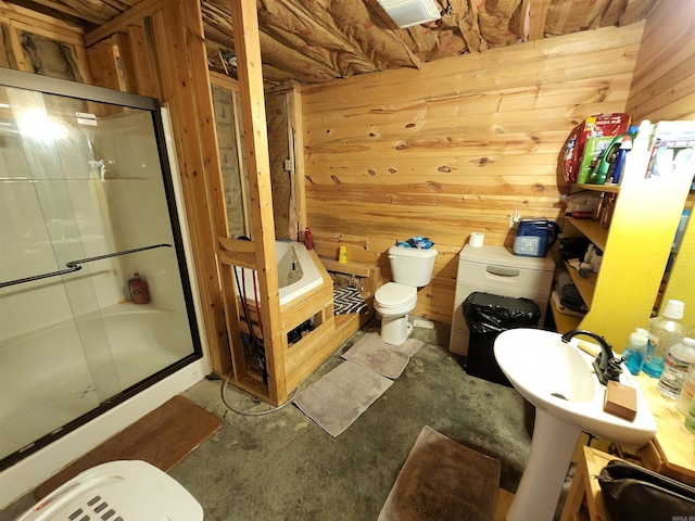 bathroom with concrete flooring, toilet, wood walls, and a shower with shower door