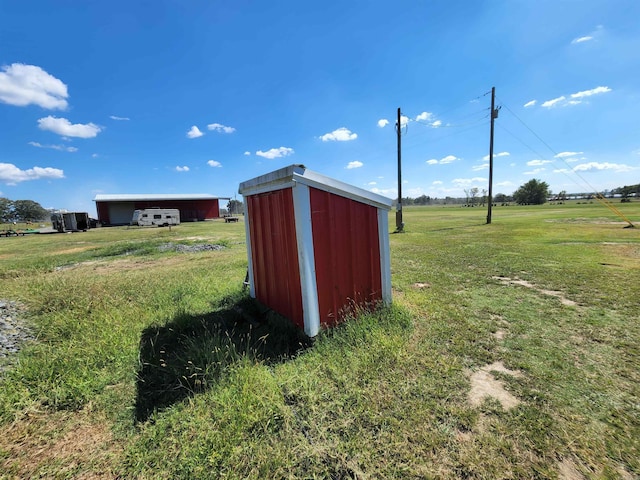 view of outdoor structure with a rural view and a yard