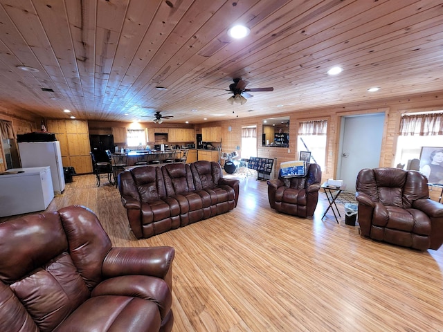 living room featuring wooden walls, light hardwood / wood-style floors, ceiling fan, and wood ceiling