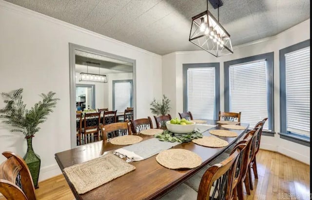 dining area with an inviting chandelier, crown molding, and light hardwood / wood-style floors