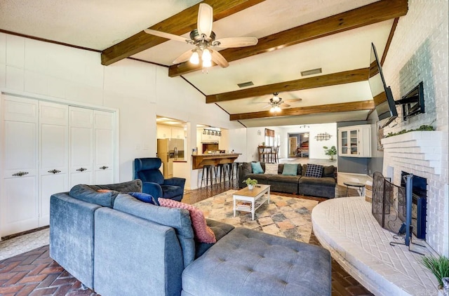 living room featuring beamed ceiling, ceiling fan, and a brick fireplace