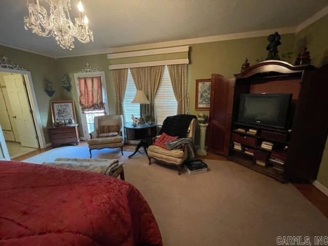 carpeted bedroom with ornamental molding and a chandelier