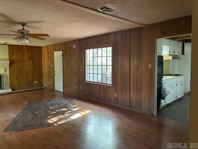 empty room with wooden walls, ceiling fan, and dark wood-type flooring