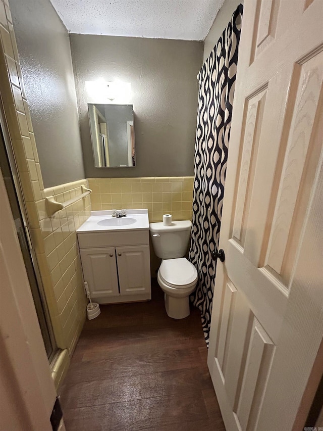 bathroom featuring vanity, tile walls, a textured ceiling, tasteful backsplash, and hardwood / wood-style flooring