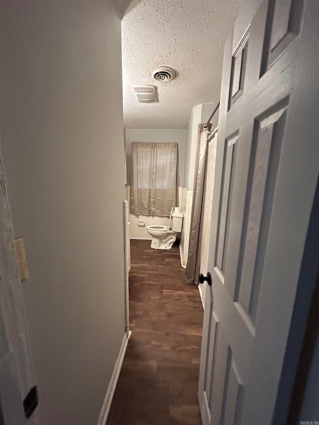 corridor with dark hardwood / wood-style floors and a textured ceiling