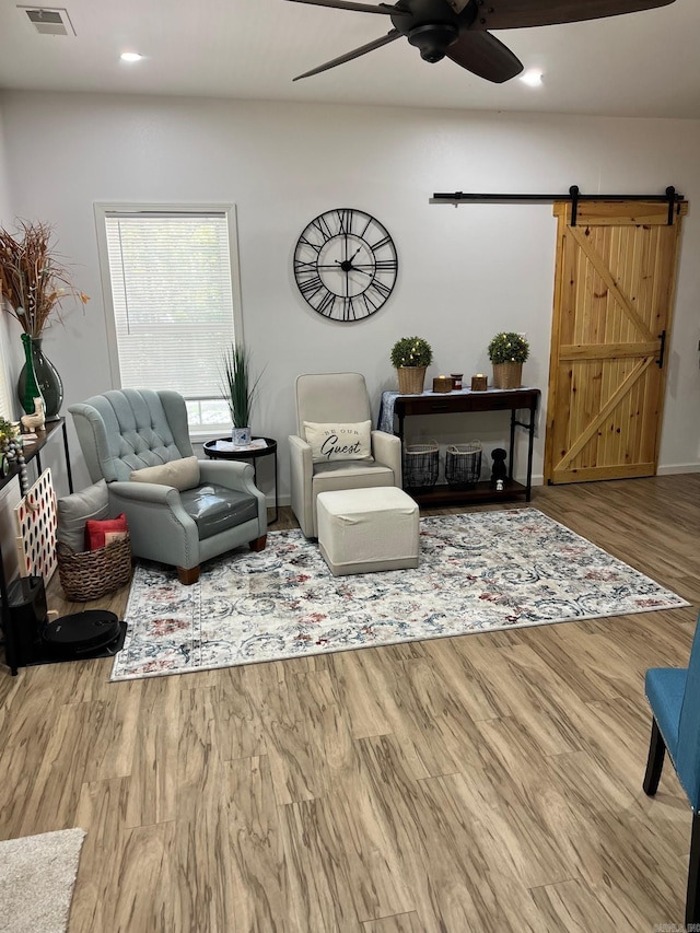 living area featuring visible vents, ceiling fan, a barn door, recessed lighting, and wood finished floors