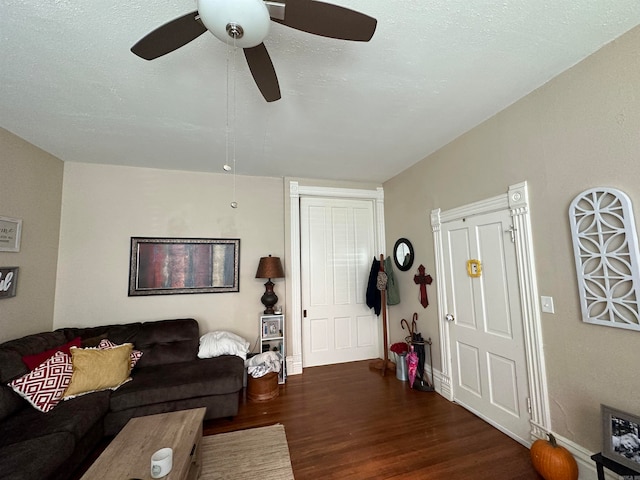 living room featuring ceiling fan, a textured ceiling, and dark wood-type flooring