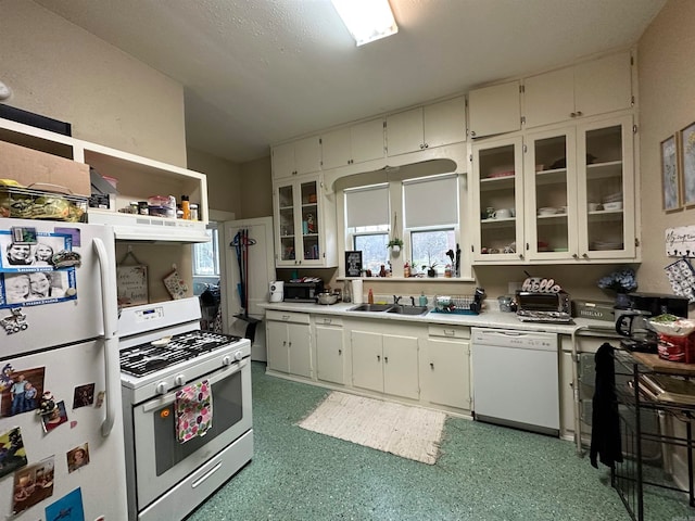 kitchen featuring sink, white appliances, white cabinetry, and dark carpet