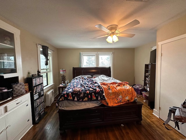 bedroom featuring a textured ceiling, dark hardwood / wood-style floors, and ceiling fan