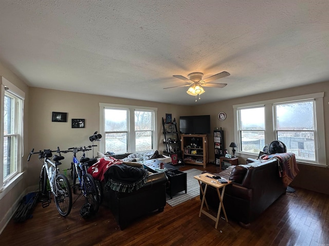 living room featuring dark wood-type flooring, a textured ceiling, and ceiling fan