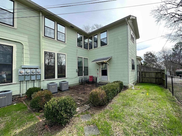 back of property featuring a yard and central AC