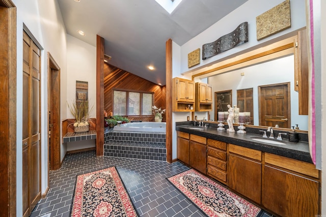 bathroom with a skylight, a relaxing tiled bath, double sink, large vanity, and tile floors