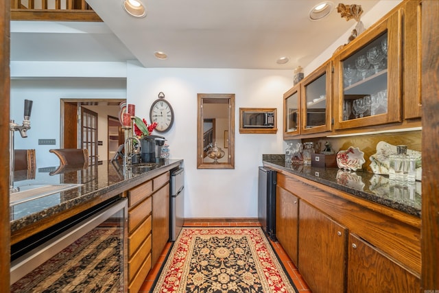 kitchen with dark stone countertops, beverage cooler, and sink