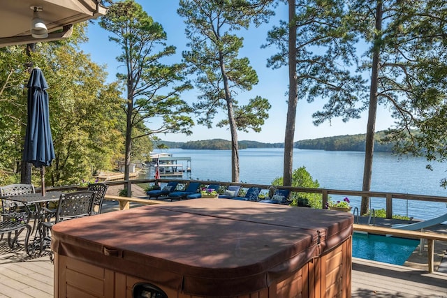 wooden deck with a water view and a hot tub