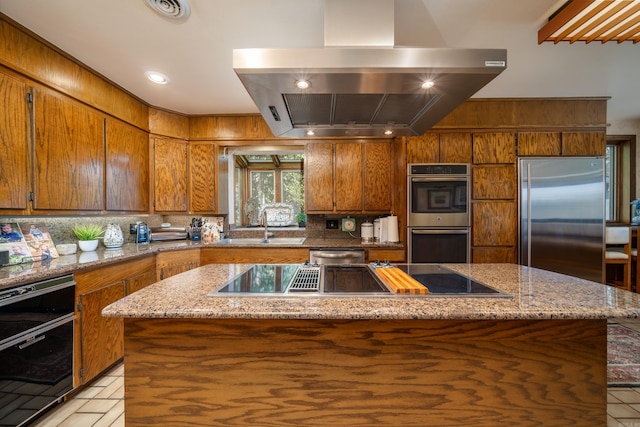 kitchen featuring backsplash, appliances with stainless steel finishes, sink, light stone counters, and island range hood