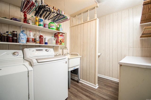 laundry area with washer and clothes dryer, dark wood-type flooring, wood walls, and a textured ceiling