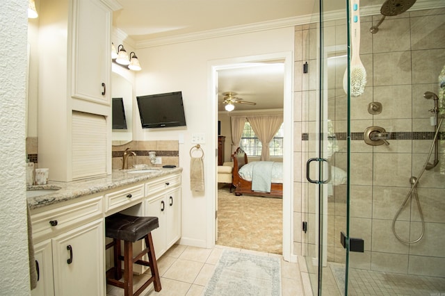 bathroom featuring dual vanity, a shower with door, ceiling fan, crown molding, and tile floors