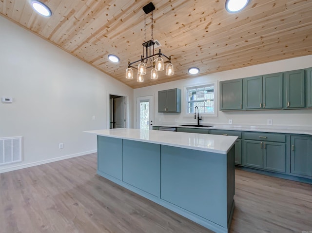 kitchen featuring decorative light fixtures, light hardwood / wood-style floors, wood ceiling, and sink