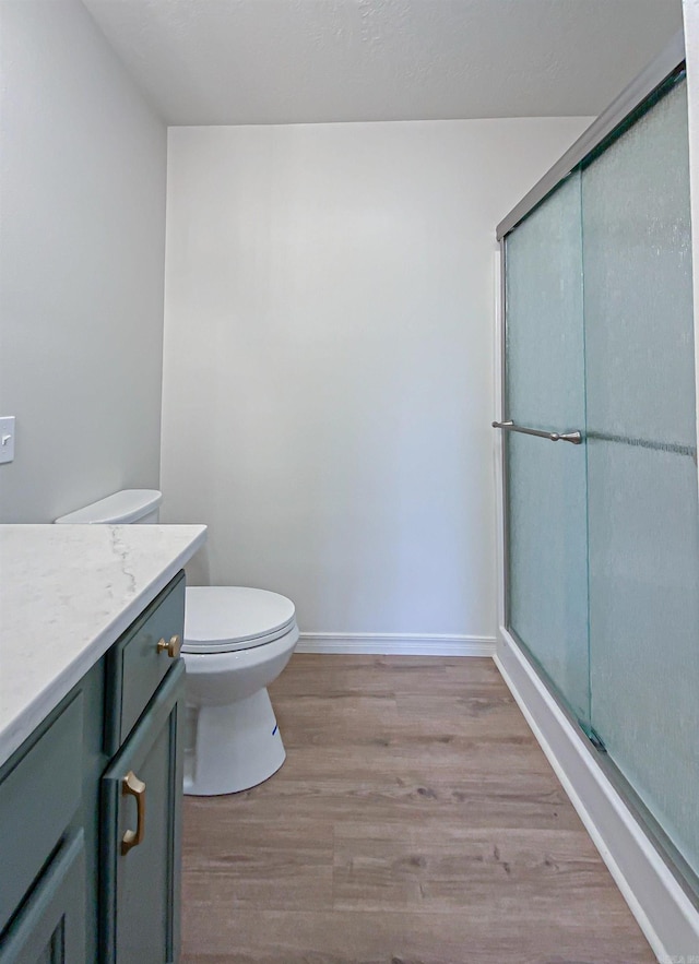 bathroom with toilet, hardwood / wood-style floors, vanity, and walk in shower