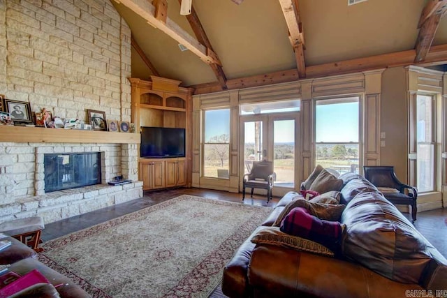 living room featuring high vaulted ceiling, plenty of natural light, beam ceiling, and a stone fireplace