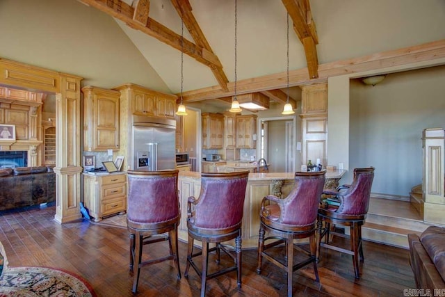 kitchen featuring stainless steel built in fridge, light stone countertops, dark wood-type flooring, high vaulted ceiling, and a kitchen bar