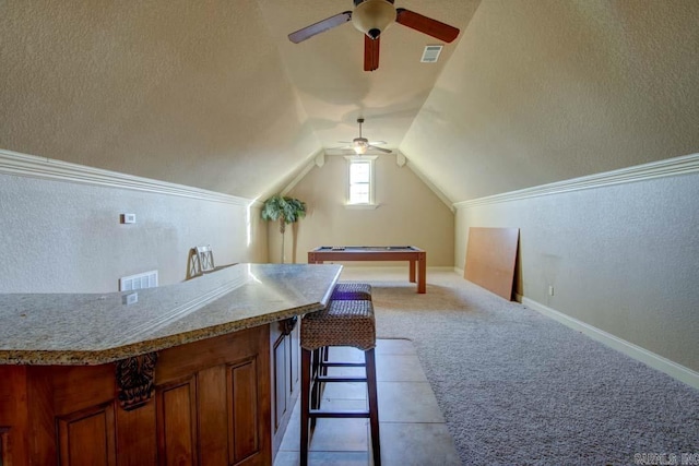 interior space with lofted ceiling, bar area, ceiling fan, and light colored carpet